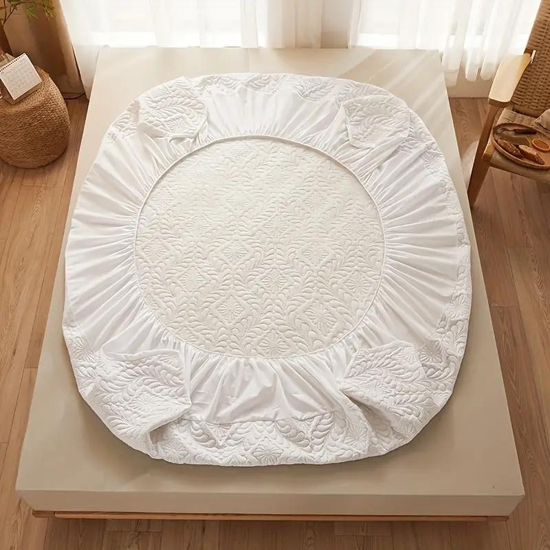 White quilted round ottoman cover on a wooden table with a light background