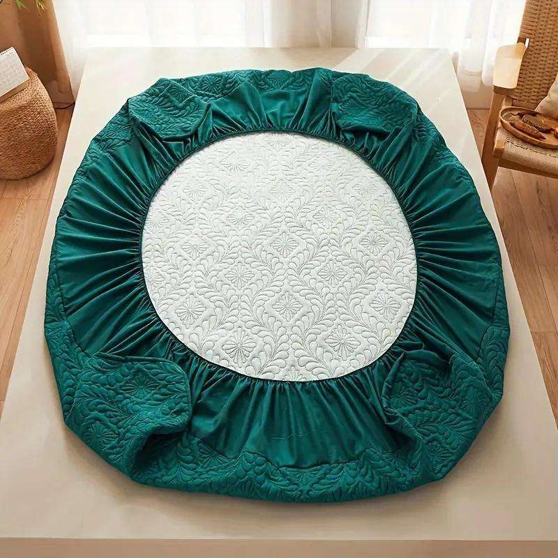 Teal round mattress cover on a white surface with a blurred background