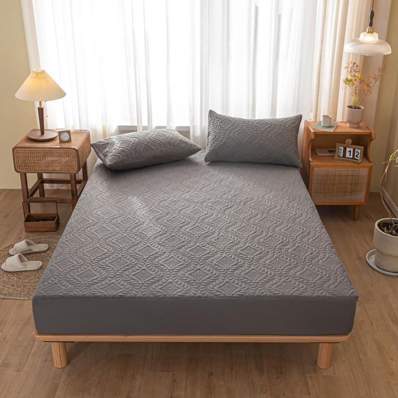 Gray mattress cover on a bed in a bedroom setting with wooden furniture and curtains.