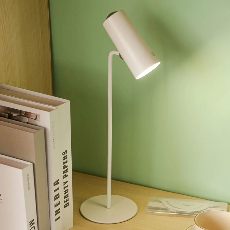 White desk lamp on a wooden surface with a green wall background